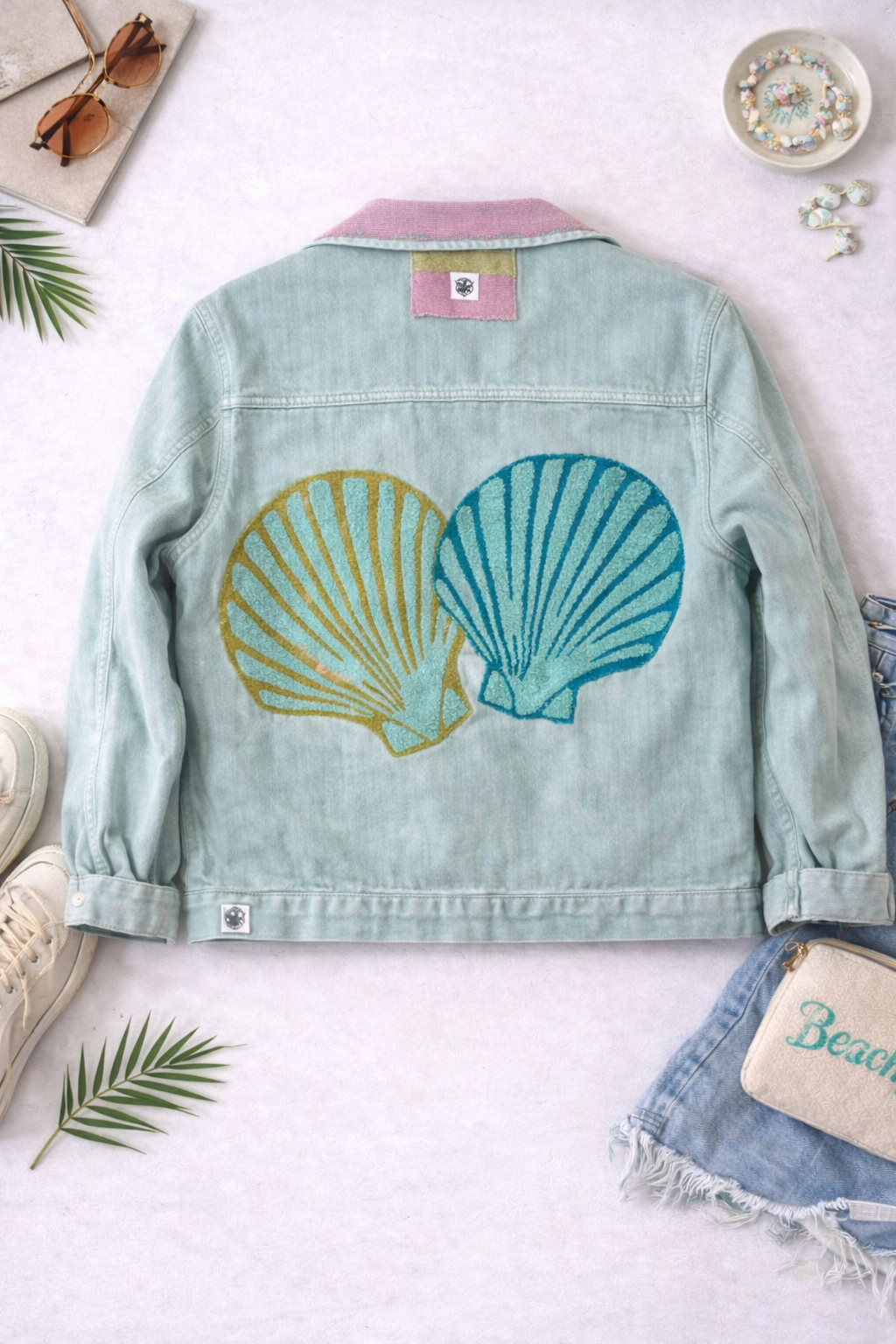 Denim jacket with shell designs on a white surface