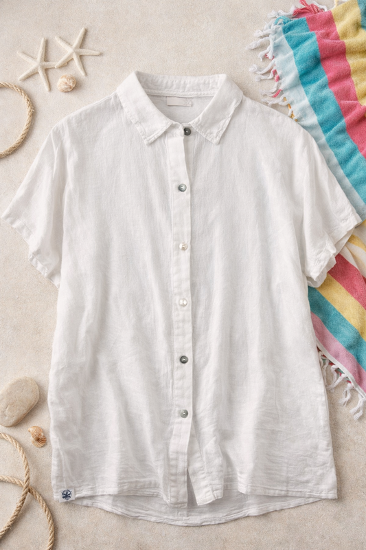White button-up shirt on a beige surface with beach-themed decor